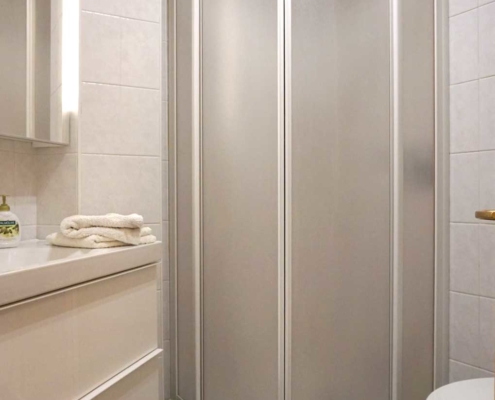 Helles Badezimmer mit weißer Dusche, WC, BD und Waschbecken stehen zur Verfügung.
